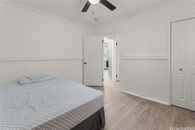 bedroom with ceiling fan, light hardwood / wood-style floors, crown molding, and a closet