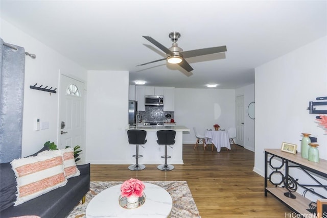 living room with dark hardwood / wood-style flooring, ceiling fan, and sink