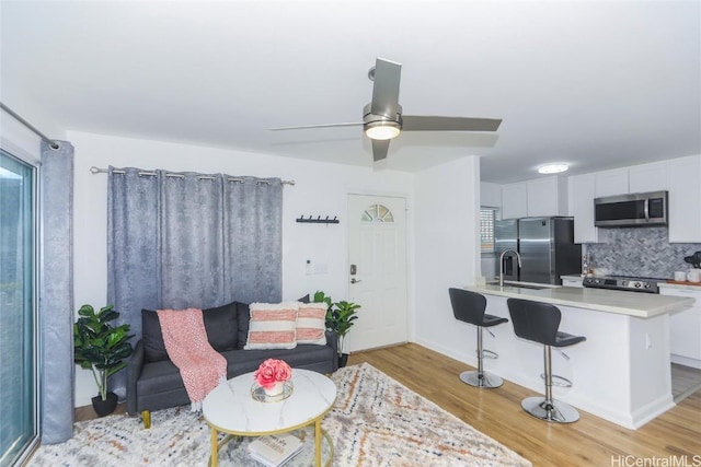 living room with ceiling fan and light wood-type flooring