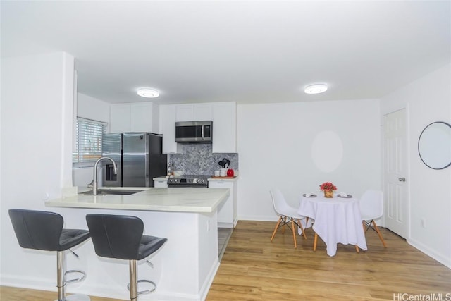 kitchen featuring white cabinets, sink, decorative backsplash, kitchen peninsula, and stainless steel appliances