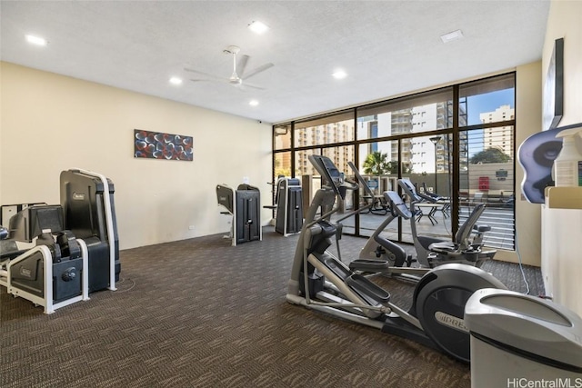 workout area with dark colored carpet, a textured ceiling, a wall of windows, and ceiling fan