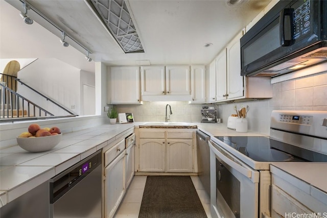 kitchen featuring decorative backsplash, sink, light tile patterned floors, and stainless steel appliances