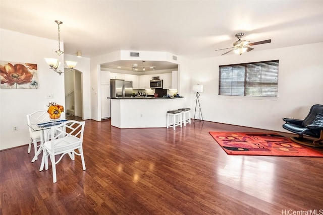 interior space featuring white cabinetry, hanging light fixtures, stainless steel appliances, kitchen peninsula, and ceiling fan with notable chandelier