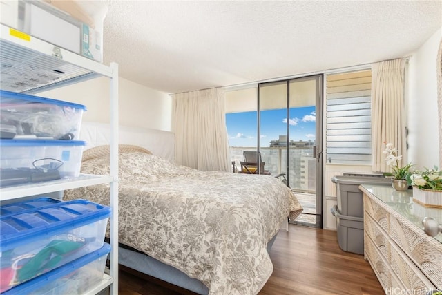 bedroom with a textured ceiling, dark hardwood / wood-style flooring, access to outside, and a wall of windows