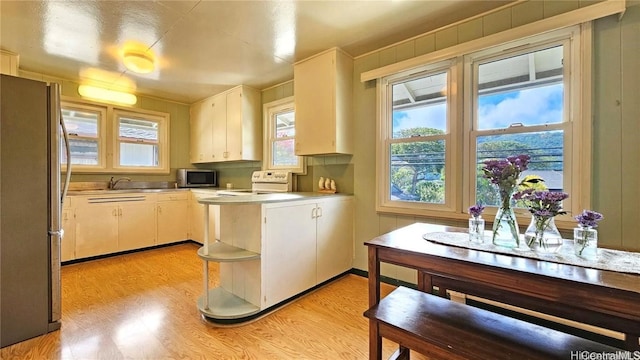 kitchen with light hardwood / wood-style floors, white cabinetry, sink, and appliances with stainless steel finishes