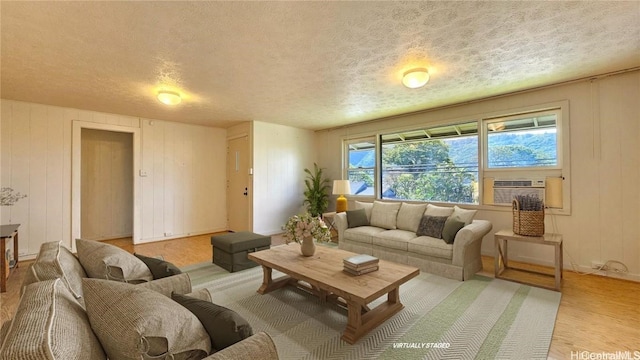 living room with a textured ceiling, light hardwood / wood-style floors, and cooling unit