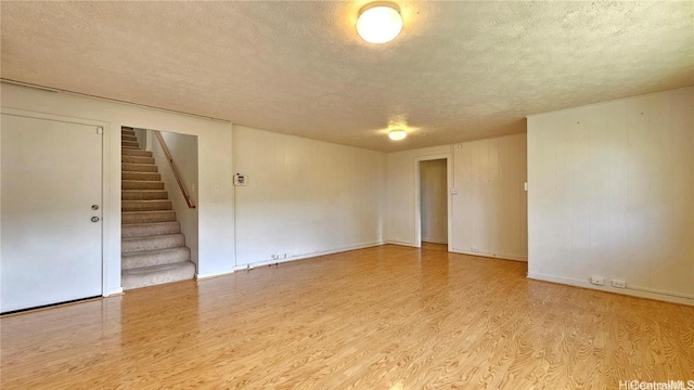 spare room with a textured ceiling and light hardwood / wood-style floors