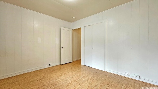 unfurnished bedroom featuring wood walls and light hardwood / wood-style floors