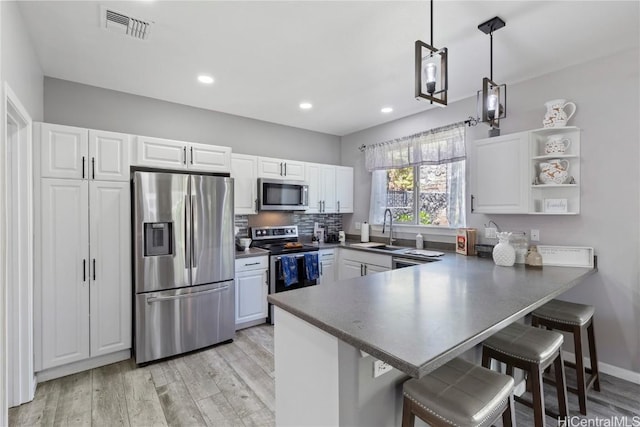 kitchen featuring kitchen peninsula, a kitchen breakfast bar, stainless steel appliances, and white cabinetry