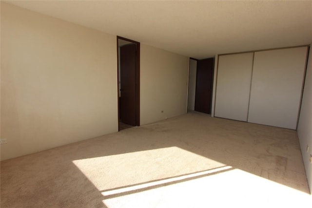 unfurnished bedroom with light colored carpet and a closet