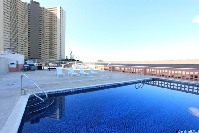 view of pool featuring a water view and a patio