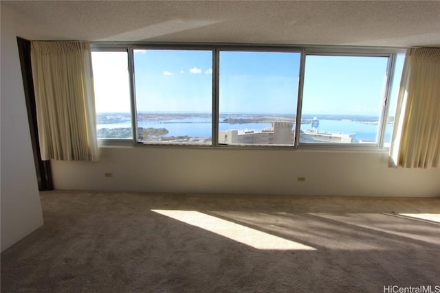 carpeted empty room featuring a water view and a textured ceiling