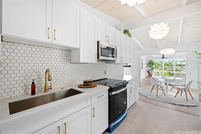 kitchen with sink, pendant lighting, white cabinets, range with electric cooktop, and backsplash