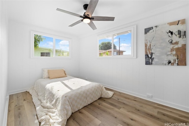 bedroom featuring multiple windows, hardwood / wood-style floors, and ceiling fan