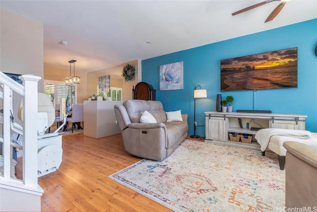 living room featuring ceiling fan with notable chandelier and wood finished floors