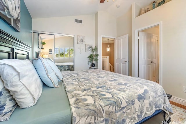 bedroom with lofted ceiling, wood finished floors, visible vents, a ceiling fan, and a closet