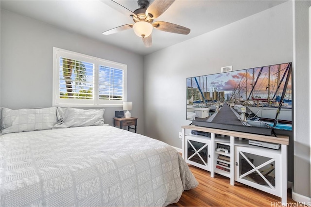 bedroom with a ceiling fan, baseboards, and wood finished floors