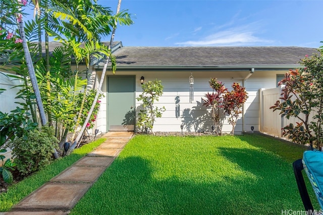 exterior space with a yard, a shingled roof, and fence