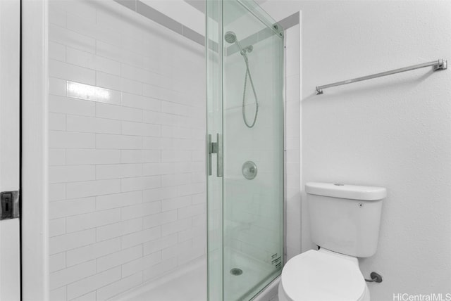 bathroom with toilet and a shower with shower door