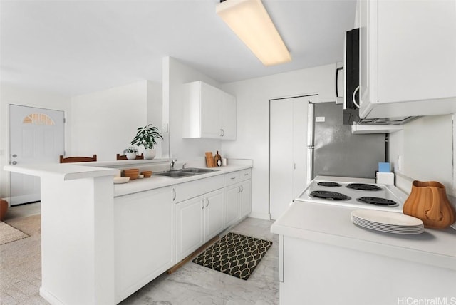 kitchen featuring white cabinetry, sink, kitchen peninsula, fridge, and a breakfast bar