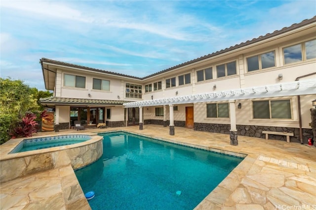 rear view of house featuring a swimming pool with hot tub and a patio