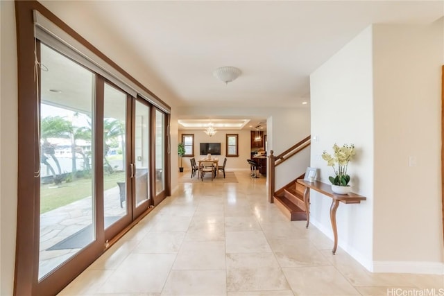 corridor with french doors, light tile patterned floors, and a notable chandelier