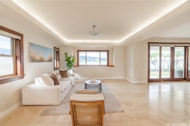 living room featuring french doors, a tray ceiling, and a wealth of natural light