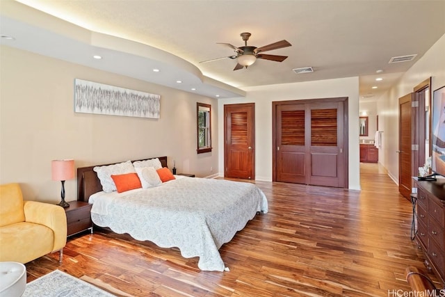 bedroom featuring ceiling fan, ensuite bathroom, and hardwood / wood-style flooring