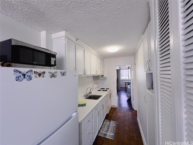 kitchen featuring sink, white appliances, a textured ceiling, and white cabinets