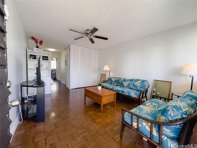 living room featuring ceiling fan, dark parquet flooring, and a textured ceiling