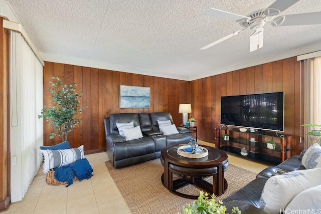 tiled living room featuring a textured ceiling, ceiling fan, and wooden walls