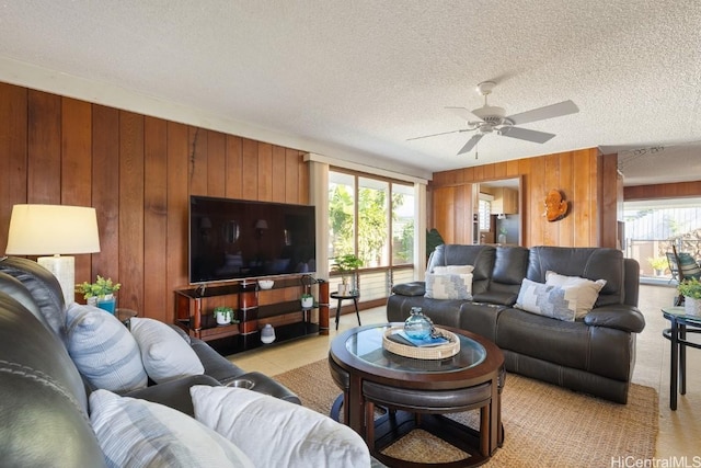 living room featuring wood walls, a healthy amount of sunlight, and a textured ceiling