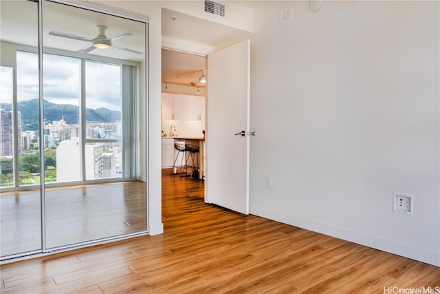 empty room with ceiling fan and light wood-type flooring