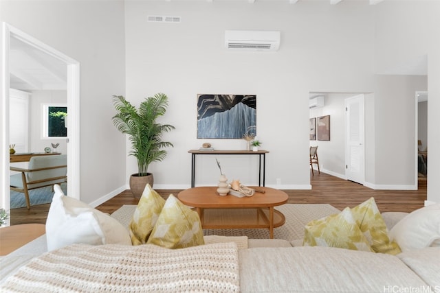 living room with a high ceiling, hardwood / wood-style flooring, and a wall mounted AC