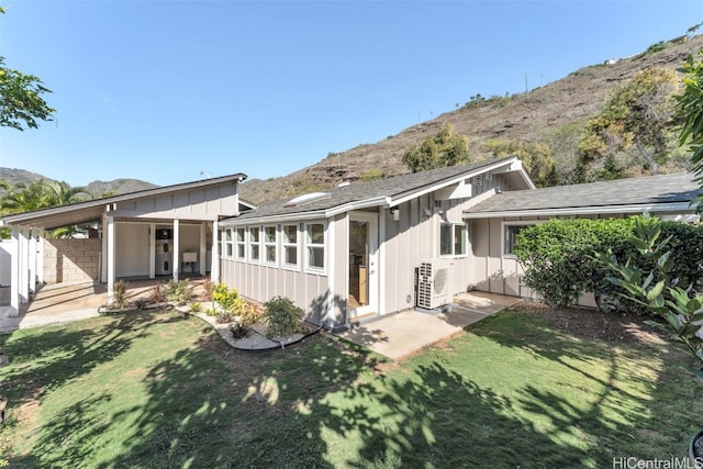 back of house with a mountain view, ac unit, and a lawn