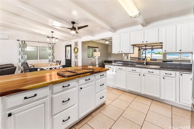 kitchen with ceiling fan, sink, beam ceiling, white cabinets, and butcher block countertops