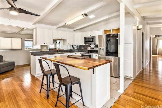 kitchen featuring wooden counters, ceiling fan, appliances with stainless steel finishes, a kitchen island, and white cabinetry