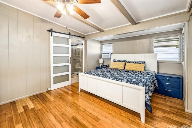 bedroom featuring ceiling fan, a barn door, beam ceiling, connected bathroom, and light hardwood / wood-style floors