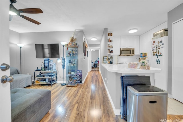 kitchen with light wood-type flooring, backsplash, white refrigerator, tile countertops, and white cabinets