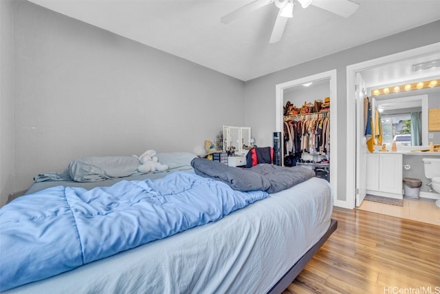 bedroom featuring ceiling fan, a closet, a spacious closet, and light hardwood / wood-style flooring