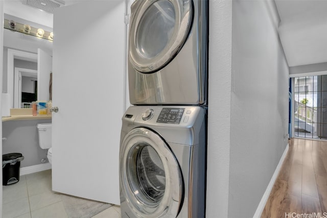 laundry room featuring light tile patterned floors and stacked washer and clothes dryer