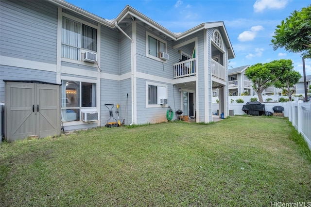 rear view of property featuring a lawn, a balcony, cooling unit, and a shed