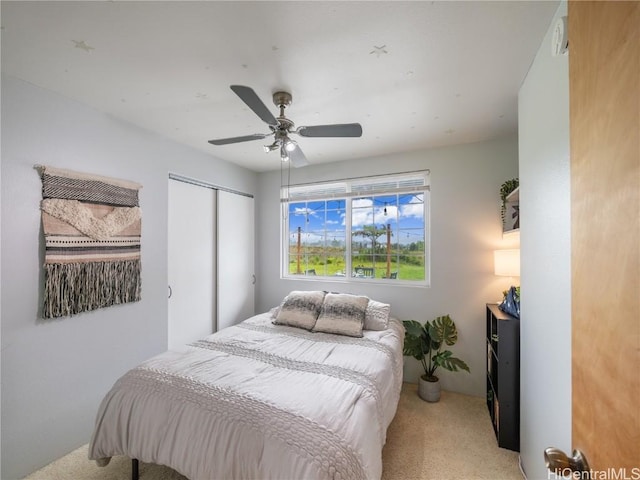 carpeted bedroom with ceiling fan and a closet