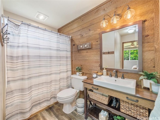 bathroom with hardwood / wood-style floors, vanity, wood walls, toilet, and walk in shower