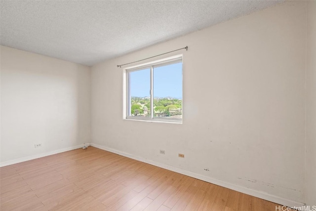 empty room with light hardwood / wood-style floors and a textured ceiling