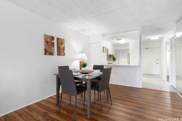 dining space featuring wood-type flooring and a textured ceiling