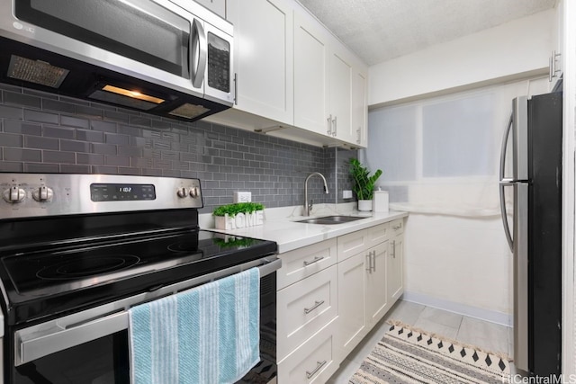 kitchen with decorative backsplash, appliances with stainless steel finishes, white cabinetry, and sink