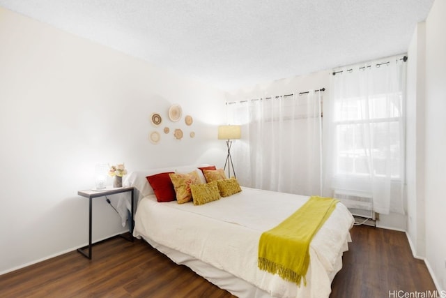 bedroom with a textured ceiling and dark hardwood / wood-style floors