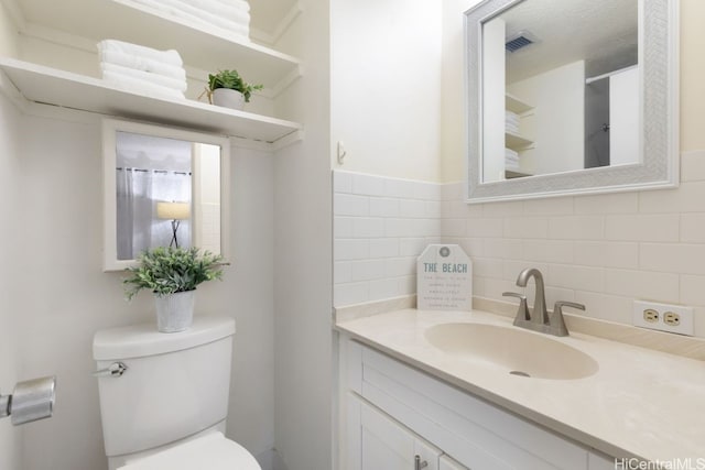 bathroom with decorative backsplash, vanity, and toilet