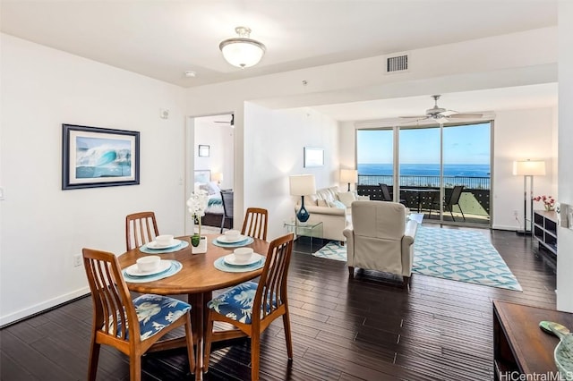 dining space featuring ceiling fan, a water view, and dark hardwood / wood-style flooring